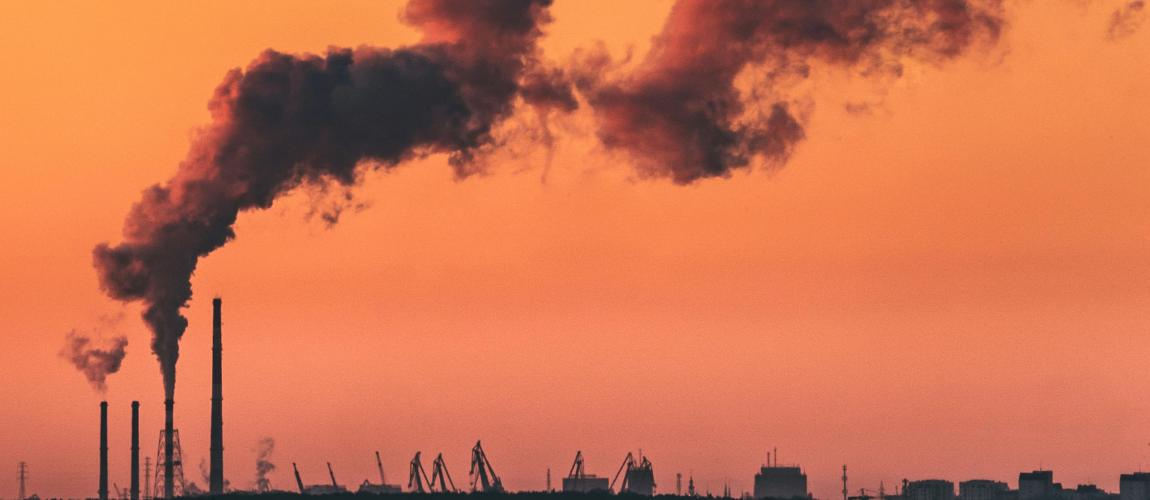 Silhouette of Smoke Stacks with smoke coming out of them, with a sunset in the background